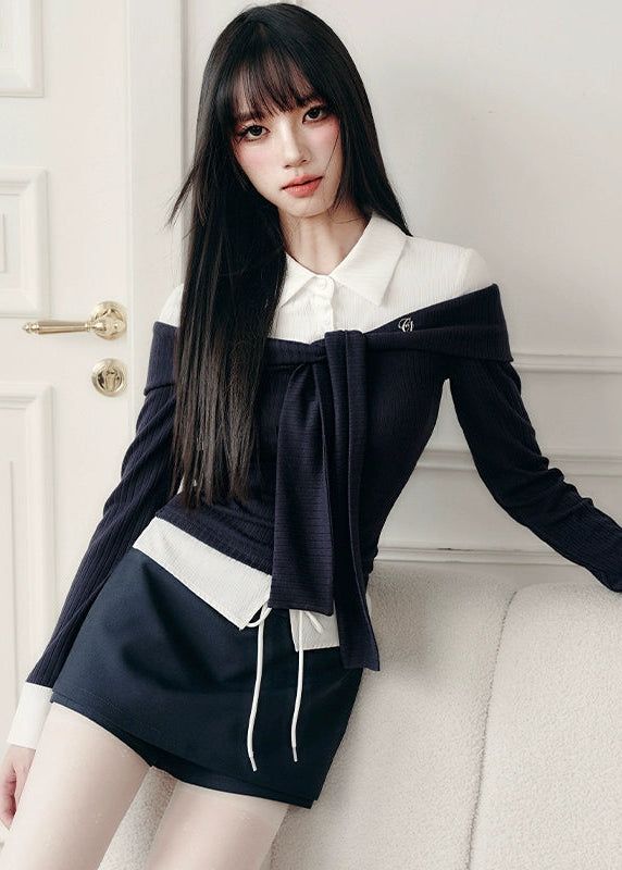 Woman with long black hair wearing an off-shoulder top and mini skirt indoors