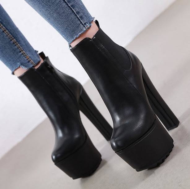Person wearing black platform ankle boots and cropped denim jeans
