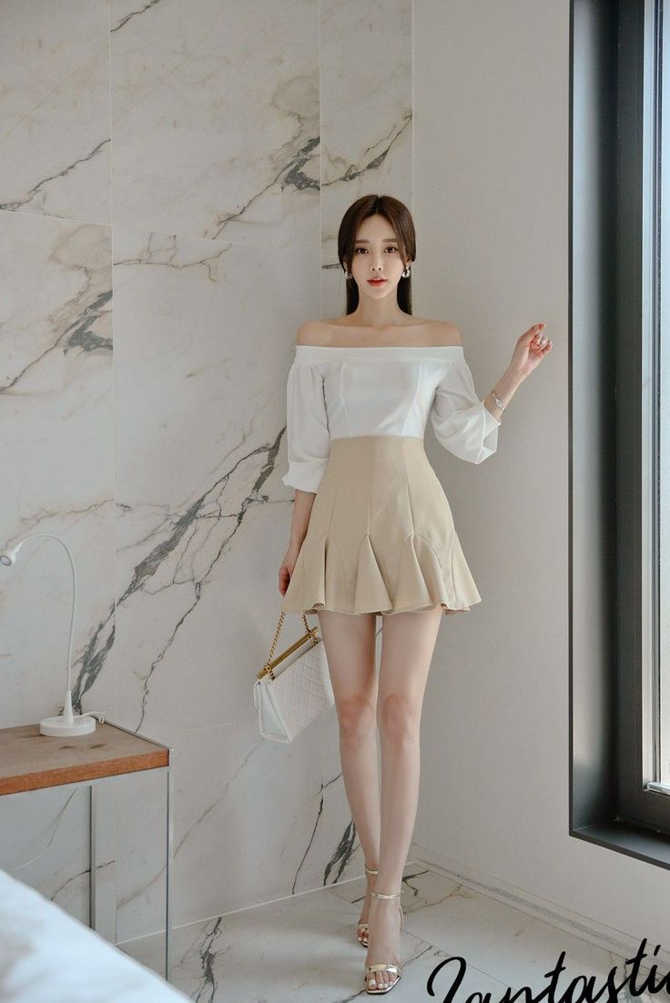 Woman in an off-shoulder top and mini skirt posing indoors