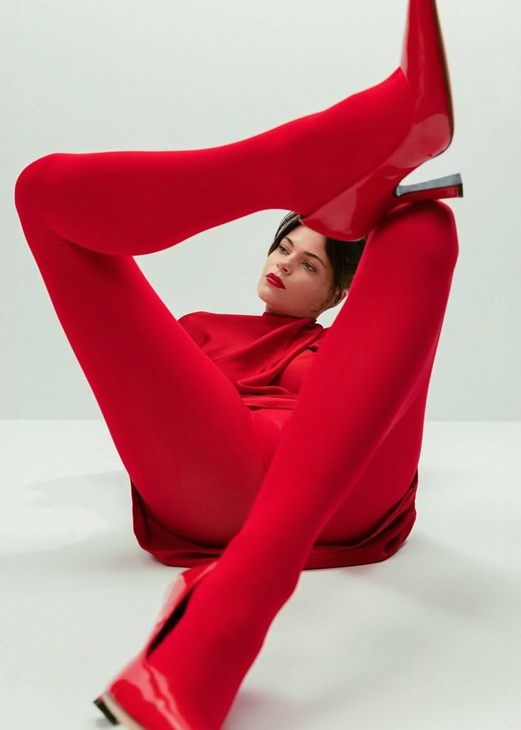 Woman in a red outfit and red boots posing provocatively in a studio