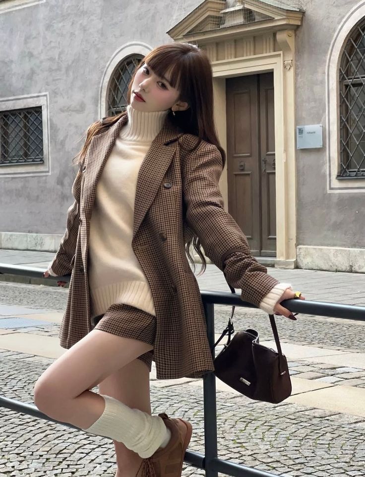 Woman in a plaid blazer and short shorts posing on a street