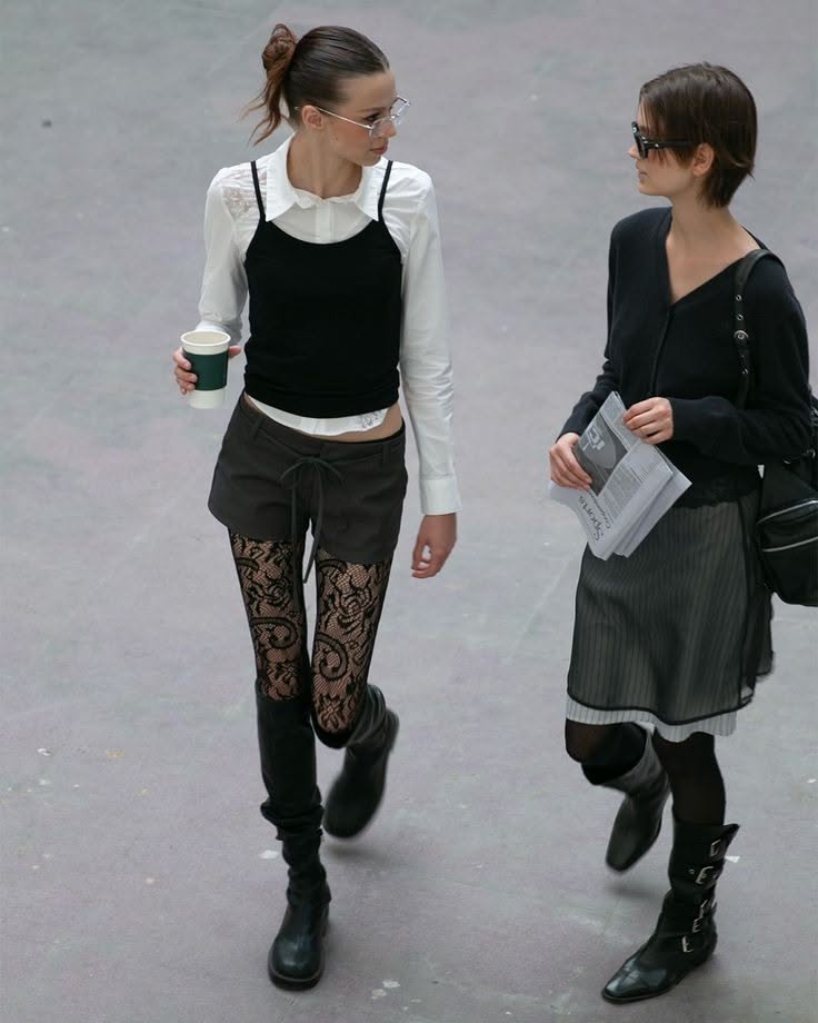 Two women walking outdoors, one with a ponytail and glasses, the other with short hair