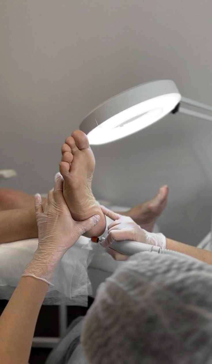 Close up of a person receiving a pedicure with a magnifying lamp