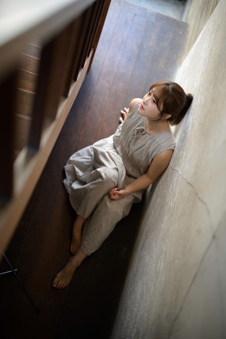 Woman with a ponytail sitting on a wooden floor indoors