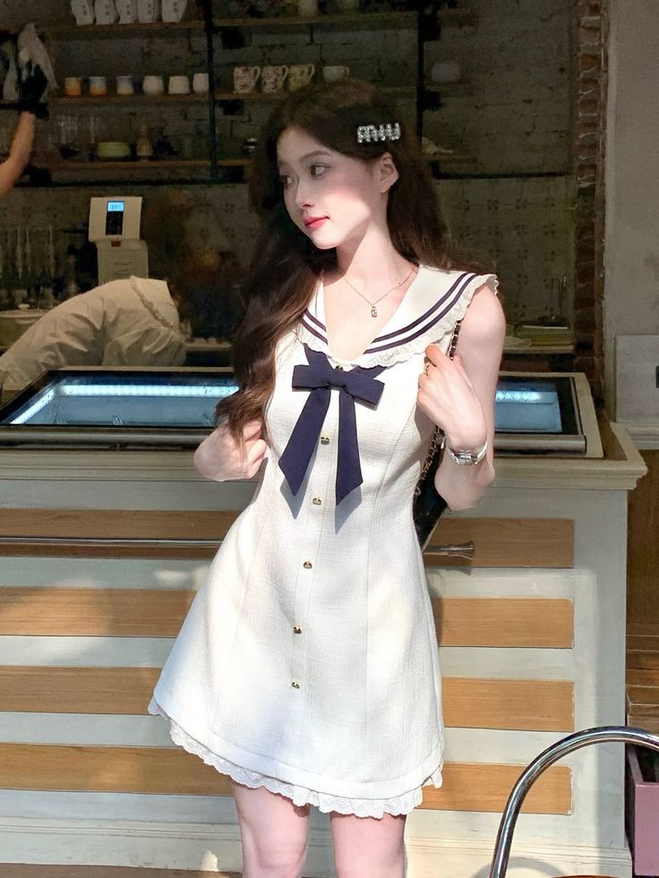Woman in a white sailor dress with a navy bow indoors