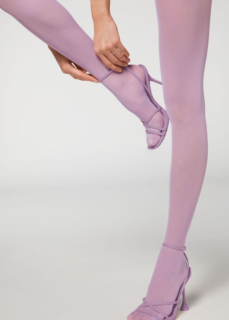 Person adjusting purple tights while wearing matching high heels