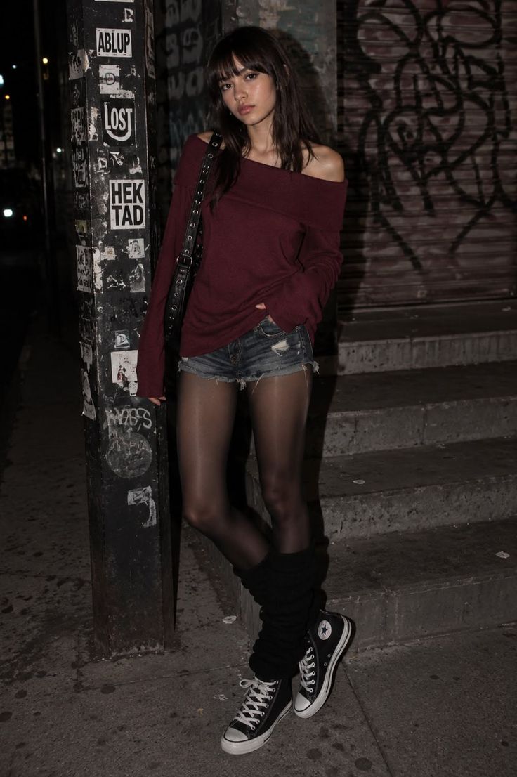 Woman in an off-shoulder top and denim shorts with tights at night