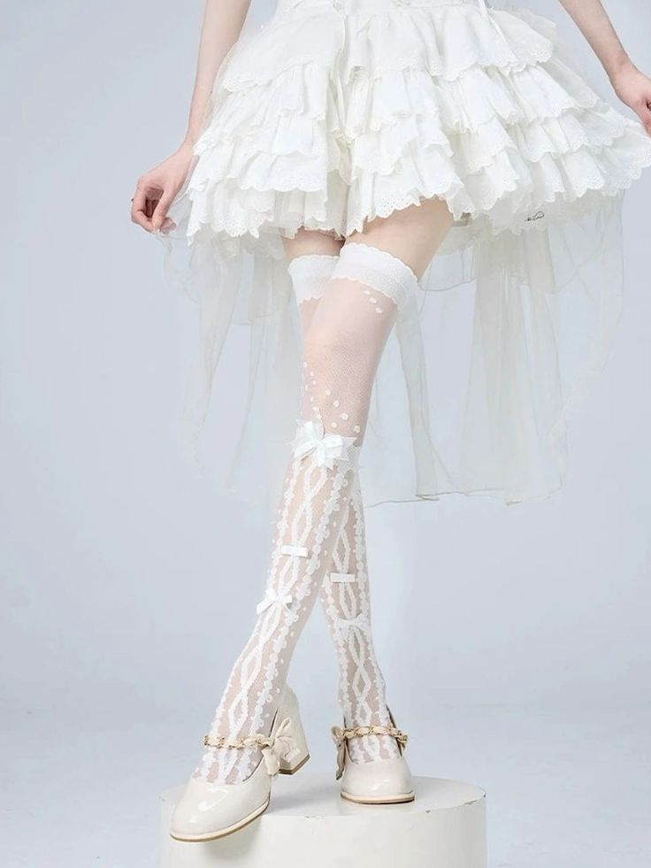 Person in a white ruffled dress and patterned thigh-high socks with bows