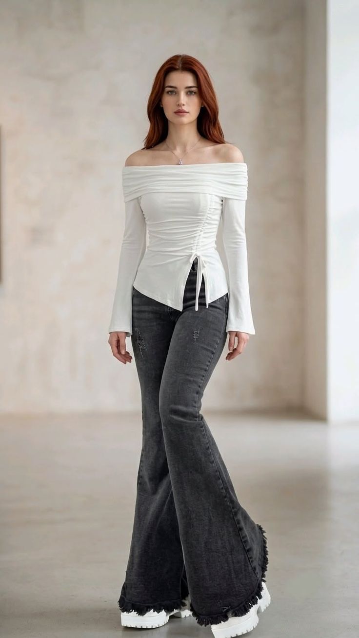 Woman with long red hair wearing an off-shoulder top and bell-bottom jeans indoors