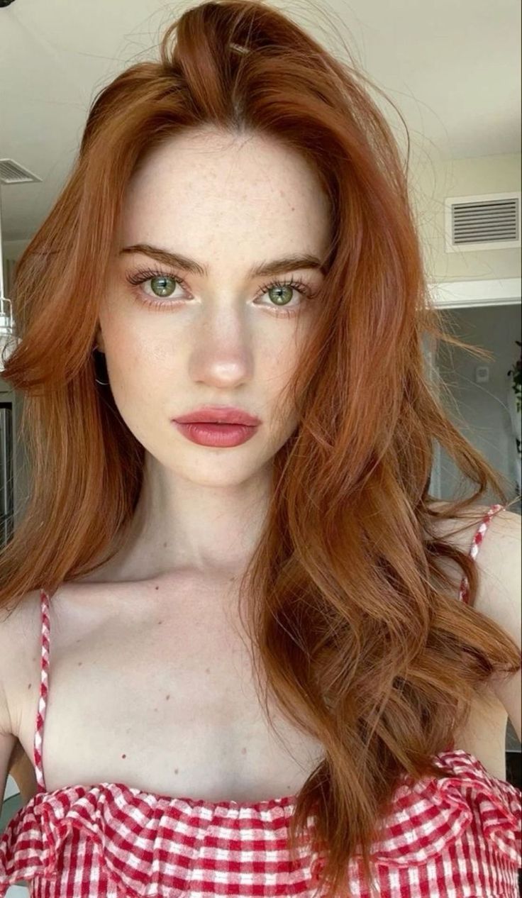 Woman with red hair and green eyes wearing a red and white gingham top