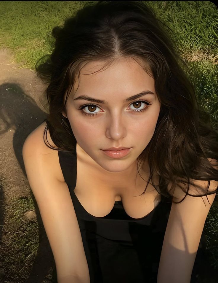 Woman with long dark hair in a black top, looking up at the camera