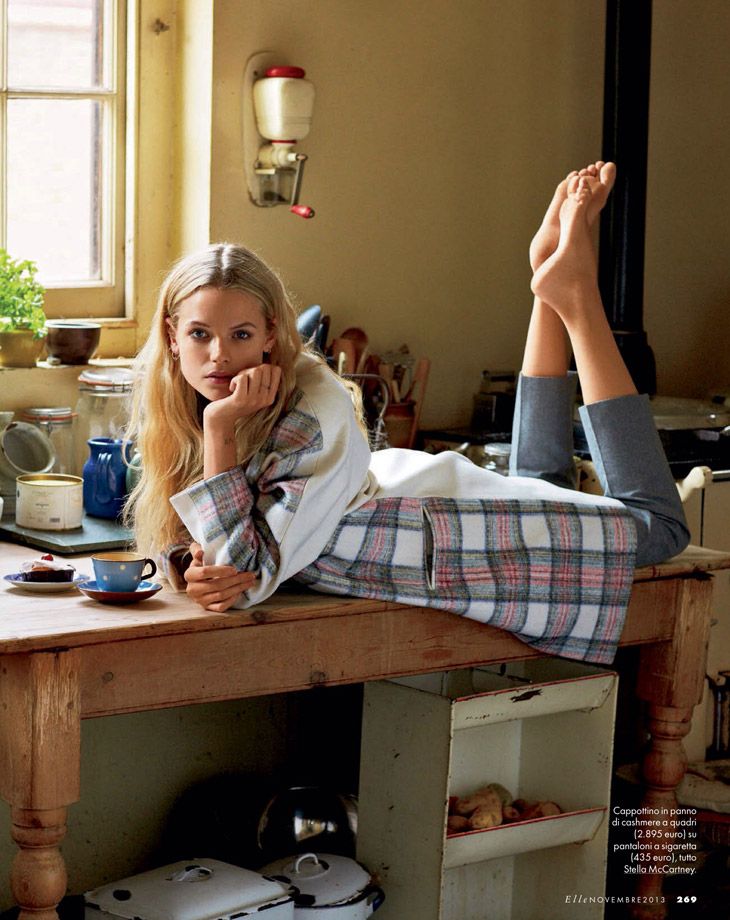 Woman with long blonde hair lying on a wooden table in a kitchen