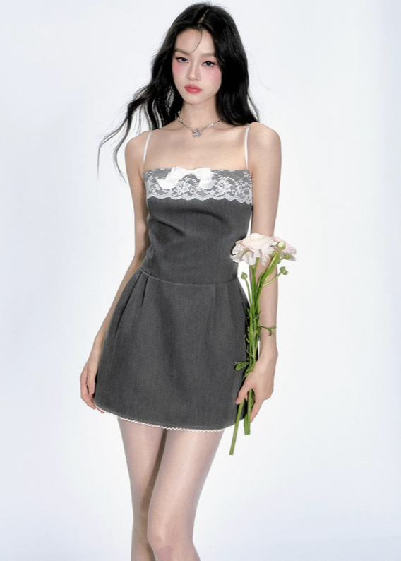 Woman in a dark gray mini dress with white lace and bow, holding flowers