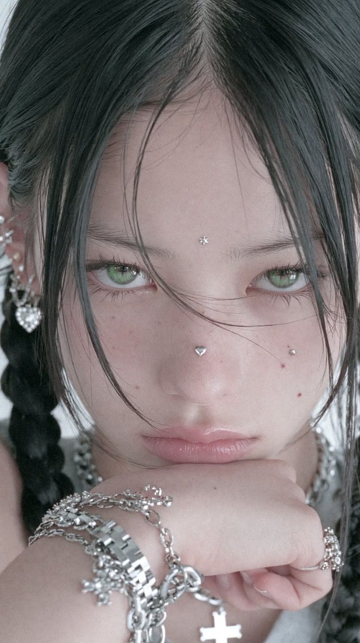 Close up portrait of a person with black hair, green eyes, and facial piercings