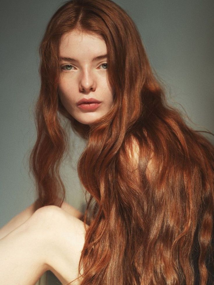 Woman with long red hair and exposed skin looking directly at the viewer