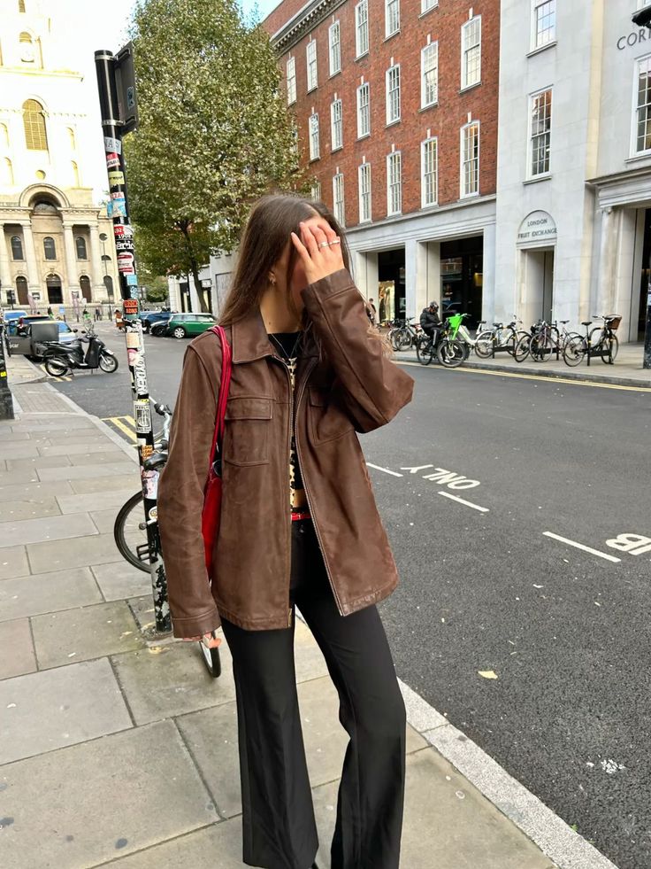 Person in a brown jacket and black pants on a city street