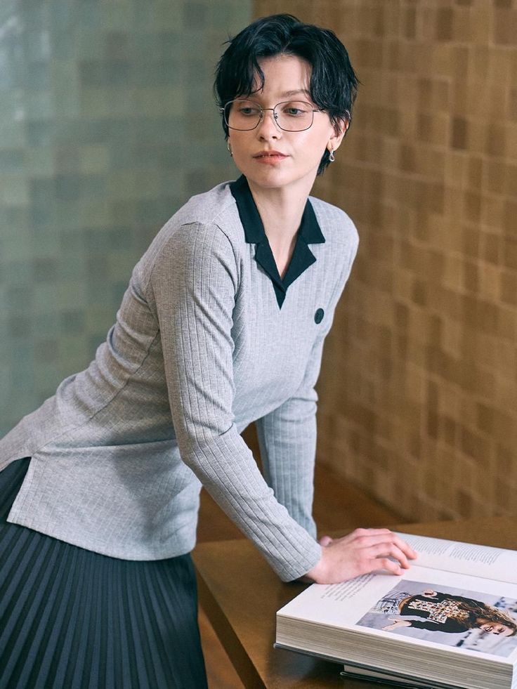 Woman with short hair and glasses leaning on a table with an open book