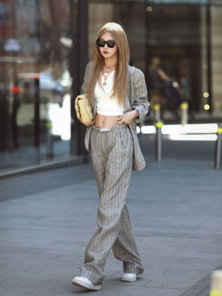 Woman in a pinstripe suit and crop top walking outdoors