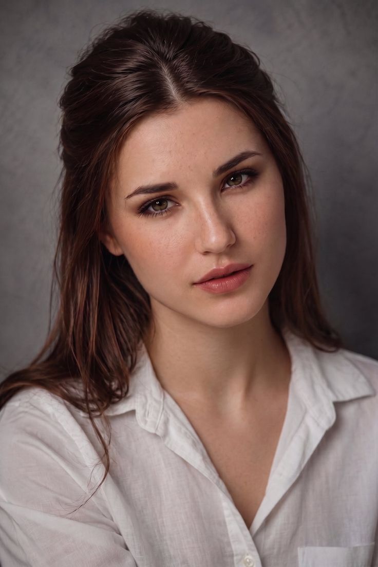 Woman with long brown hair wearing a white shirt in a studio portrait