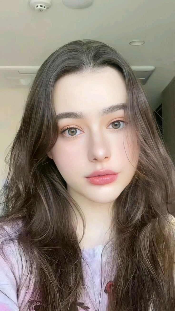 Young woman with long brown hair and light eyes in a soft lighting portrait