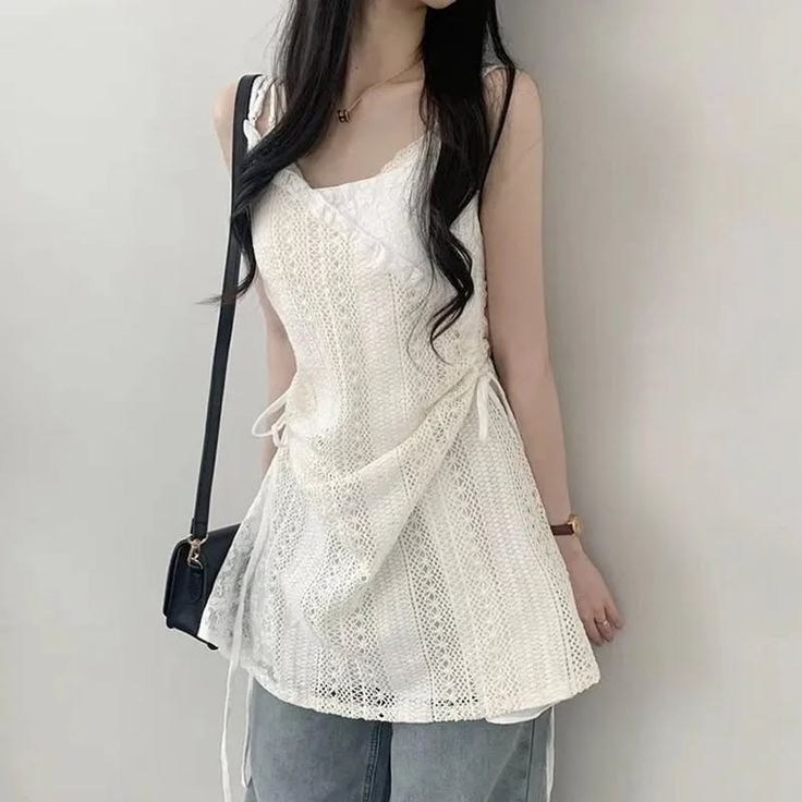 Woman with long black hair wearing a white lace top and jeans