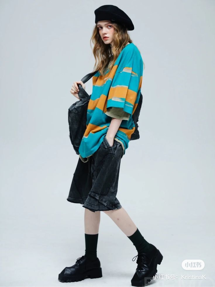 Woman in a beret, striped shirt, and denim shorts posing in a studio