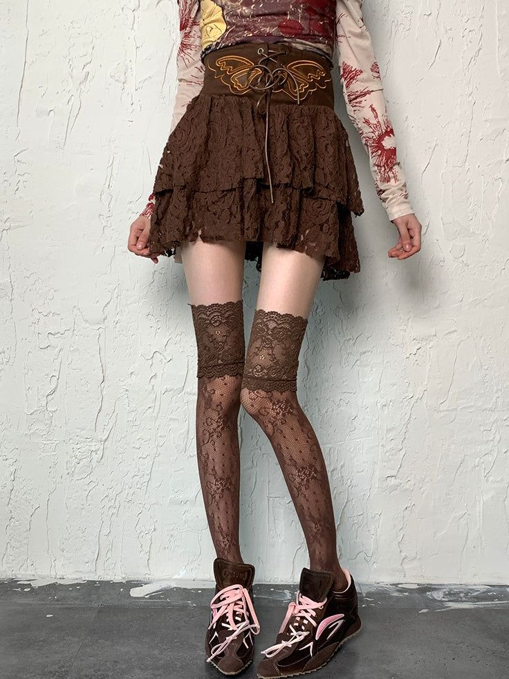 Person wearing a brown lace skirt, thigh-high stockings, and sneakers