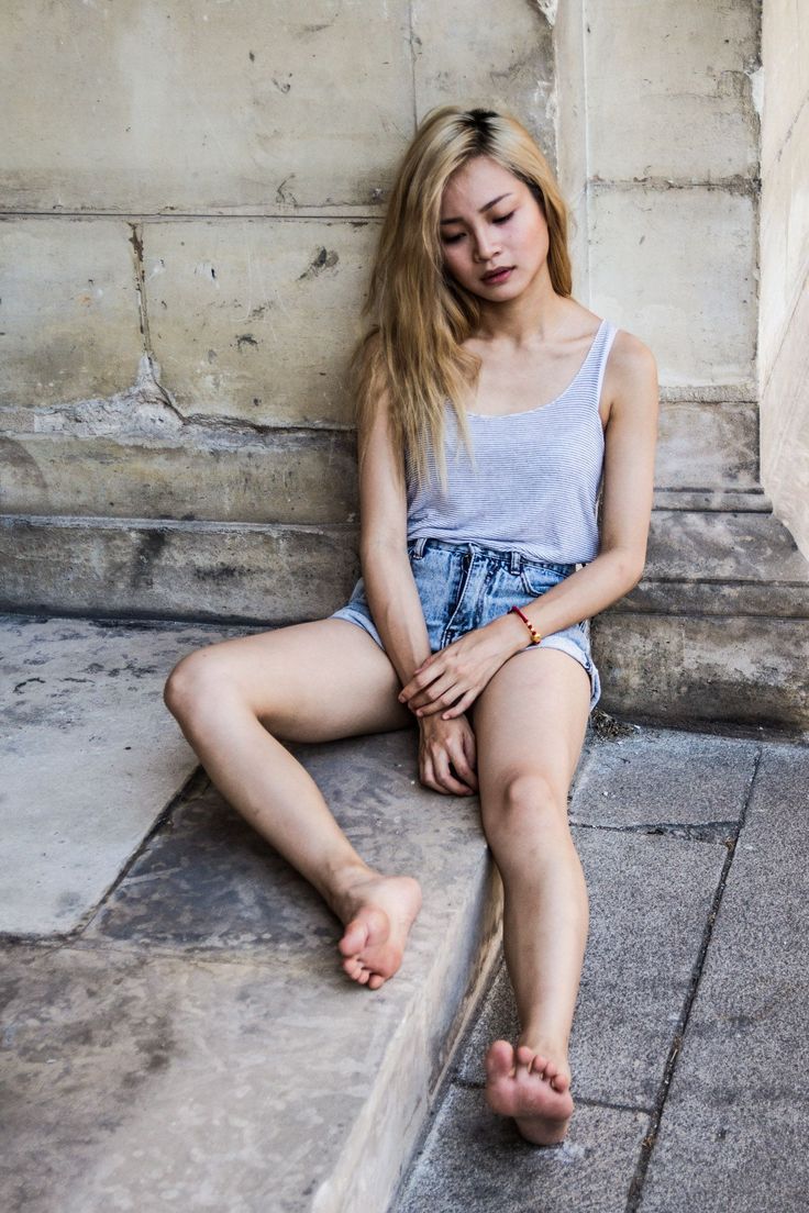 Woman with blonde hair and denim shorts sitting barefoot on stone steps