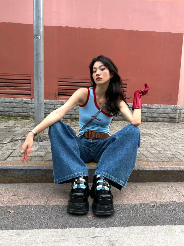 Woman in wide leg jeans and platform shoes sitting on a curb
