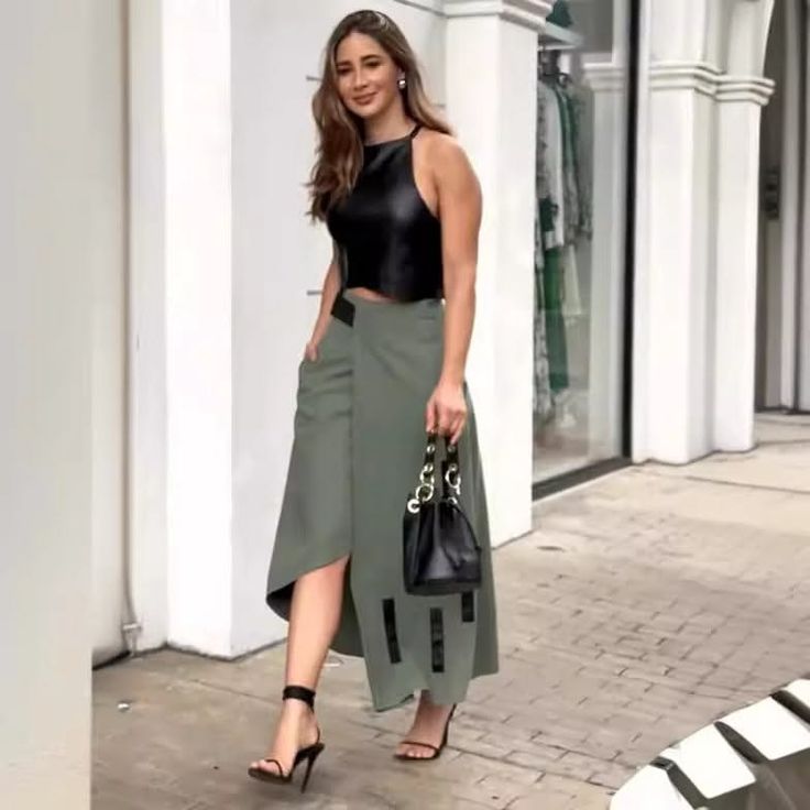Woman in a black crop top and asymmetrical skirt walking outdoors