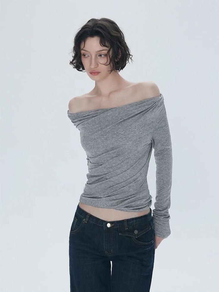 Woman with short curly hair wearing an off-shoulder top and dark wash jeans