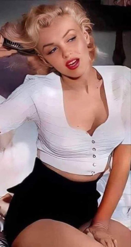 Woman with blonde hair and red lipstick in a white shirt and black skirt