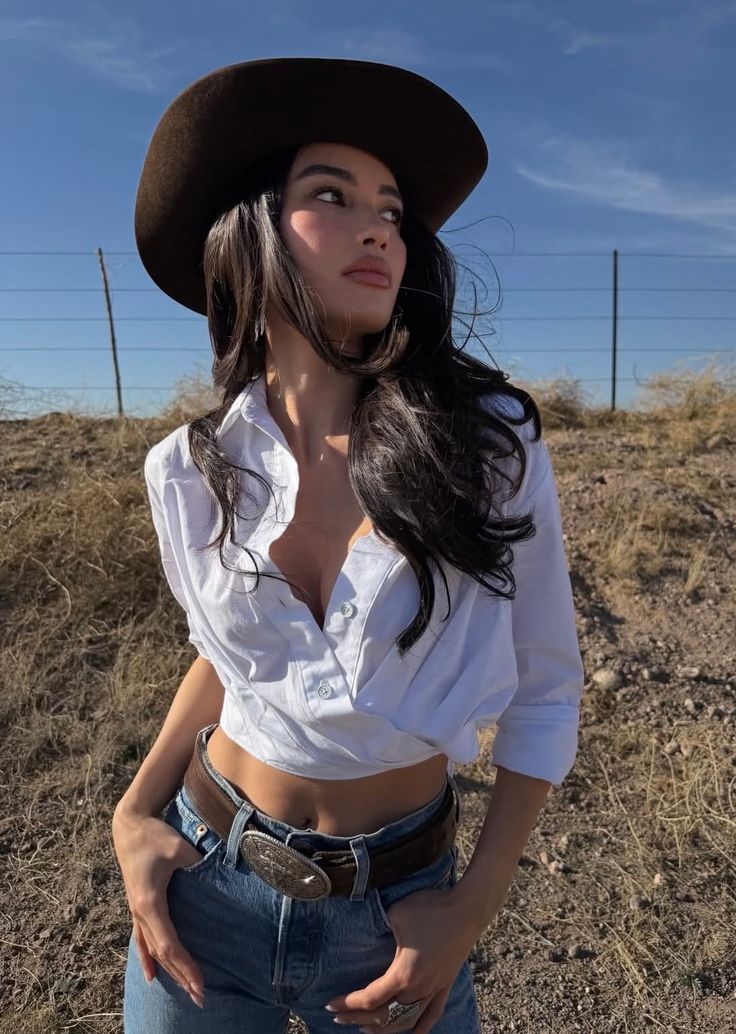 Woman in a cowboy hat and white shirt with jeans outdoors