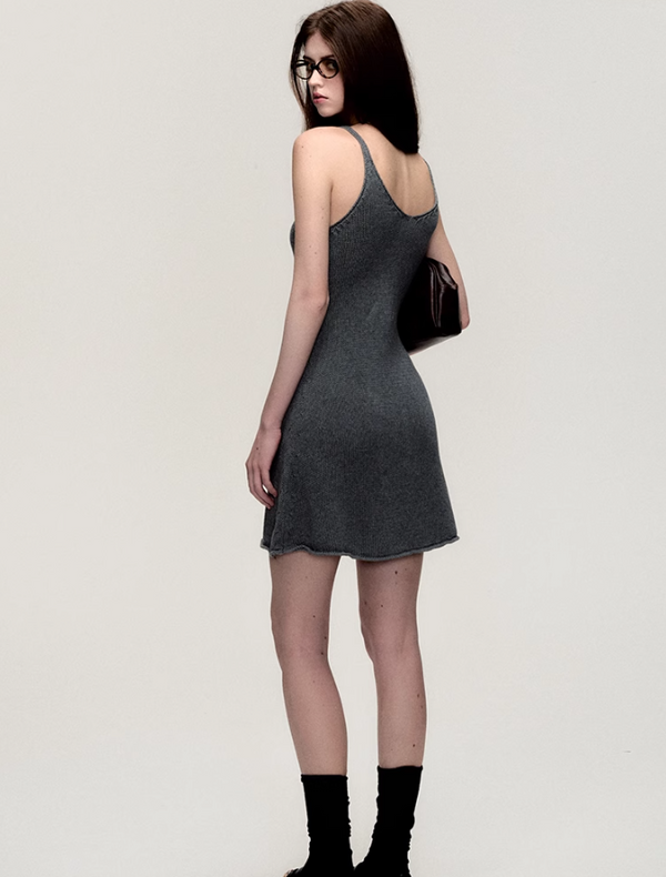 Woman in a gray dress and glasses looking over her shoulder