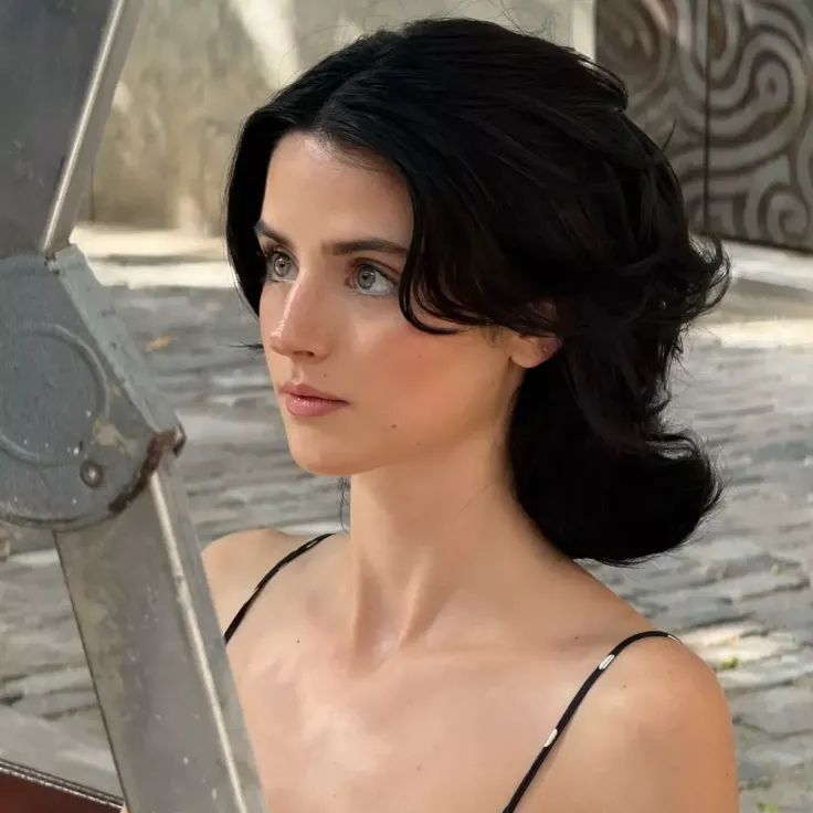 Woman with black hair in a spaghetti strap top looking to the side