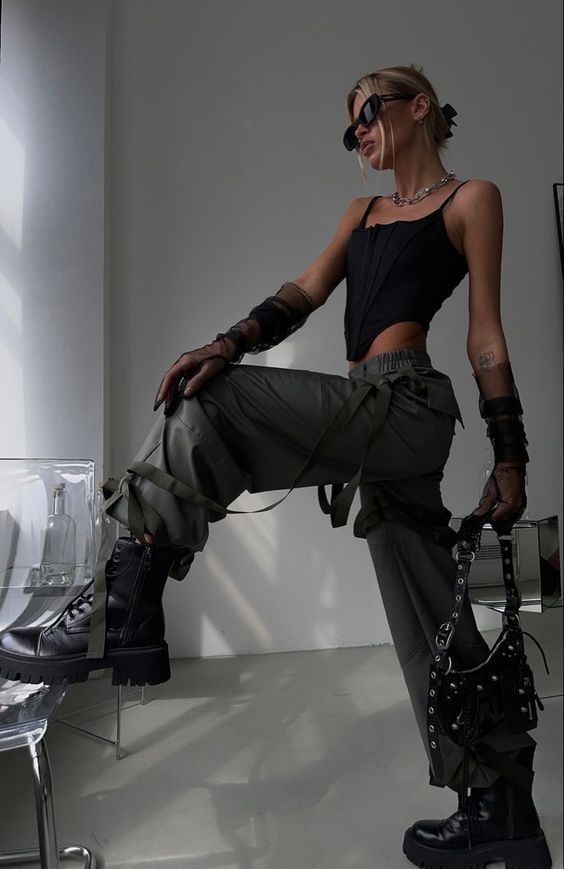 Woman in a black corset top and cargo pants posing indoors