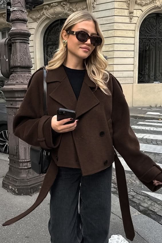 Woman in a brown jacket and sunglasses on a city street