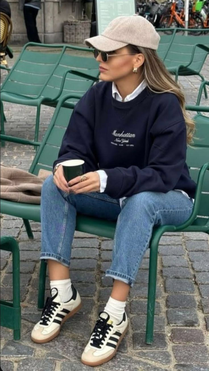 Woman in a baseball cap and sweatshirt sitting on a green chair outdoors