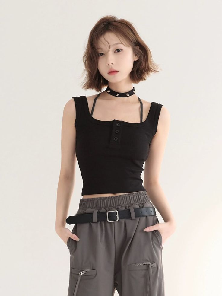 Woman with short hair wearing a black crop top and cargo pants