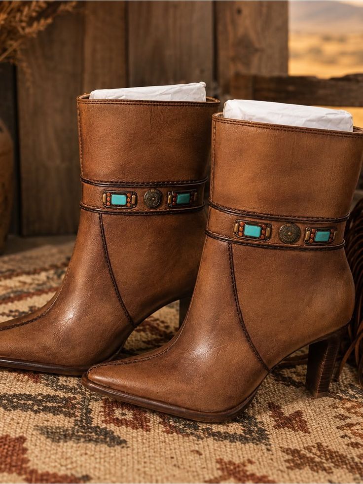 Pair of brown leather ankle boots with turquoise and metal accents on a patterned rug