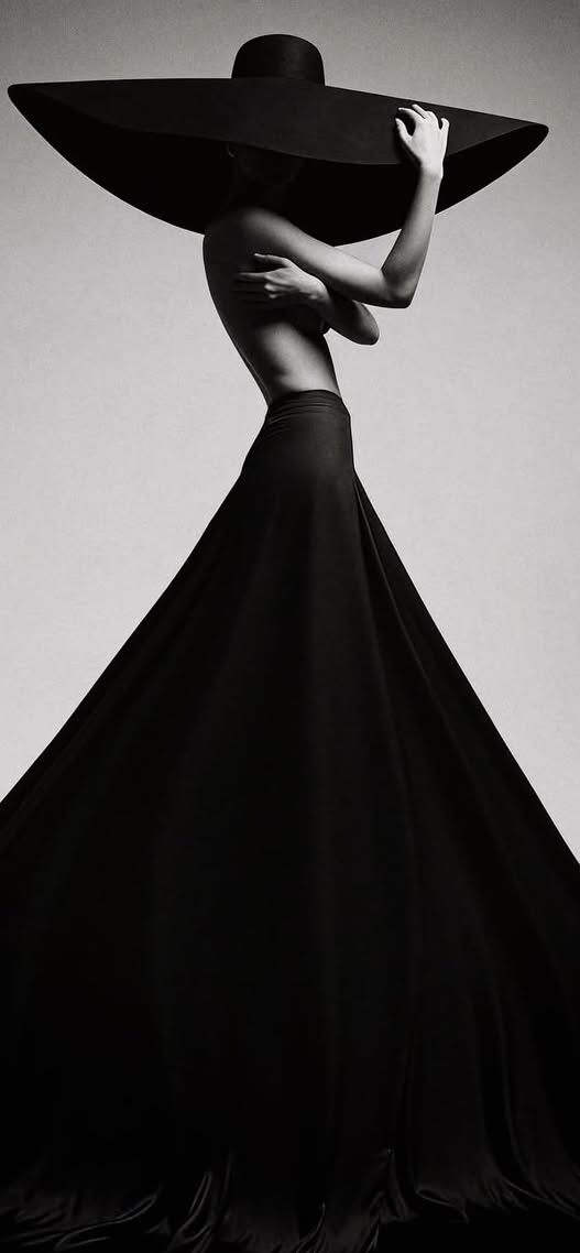 Woman in a wide brim hat and long skirt, with exposed torso, in a studio shot