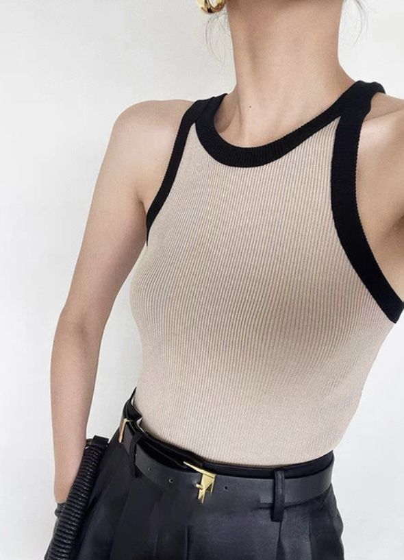 Woman in a beige ribbed sleeveless top with black trim and a black belt
