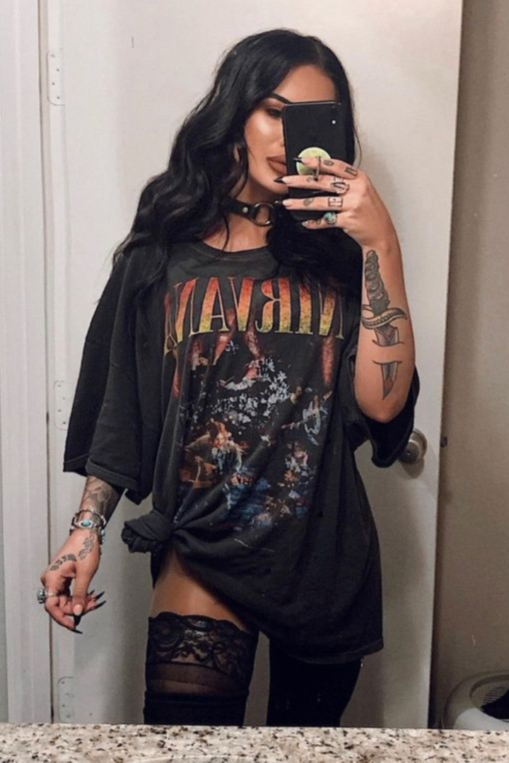 Woman in an oversized t-shirt and lace stockings taking a mirror selfie