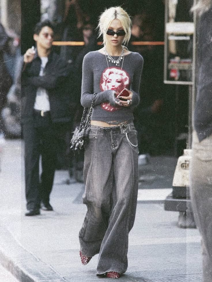 Woman with blonde hair and sunglasses wearing baggy jeans and a cropped top on a street
