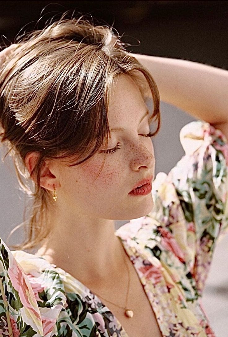 Woman with freckles and closed eyes wearing a floral dress