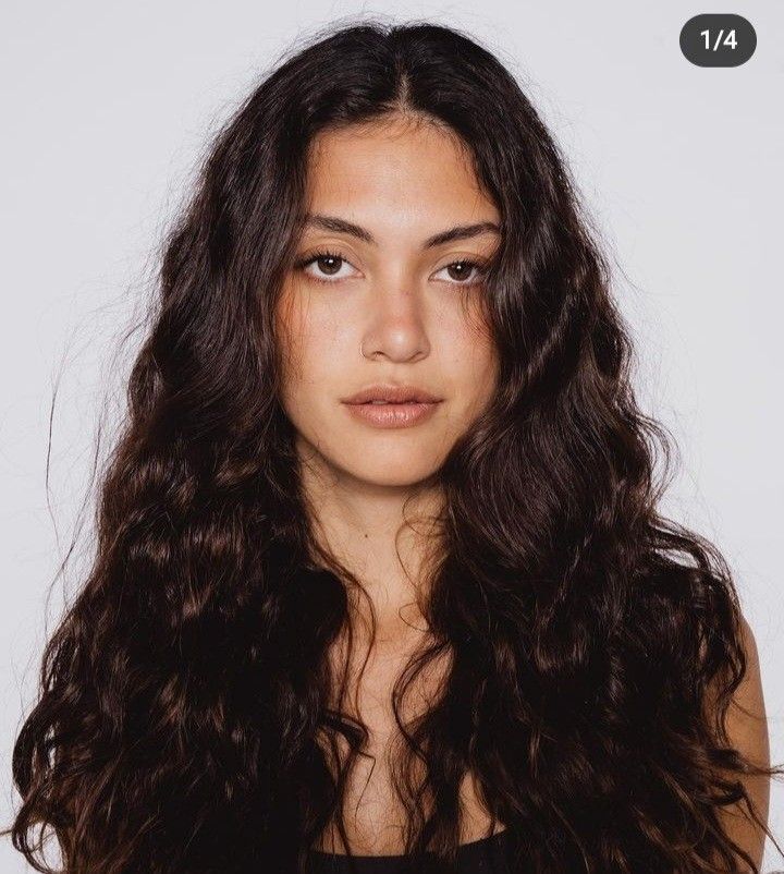 Woman with long wavy dark hair in a studio portrait with a white background