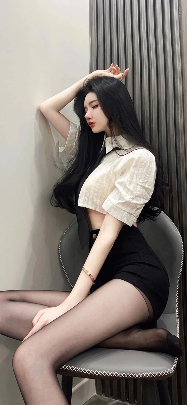 Woman with long black hair wearing a crop top and black shorts with pantyhose