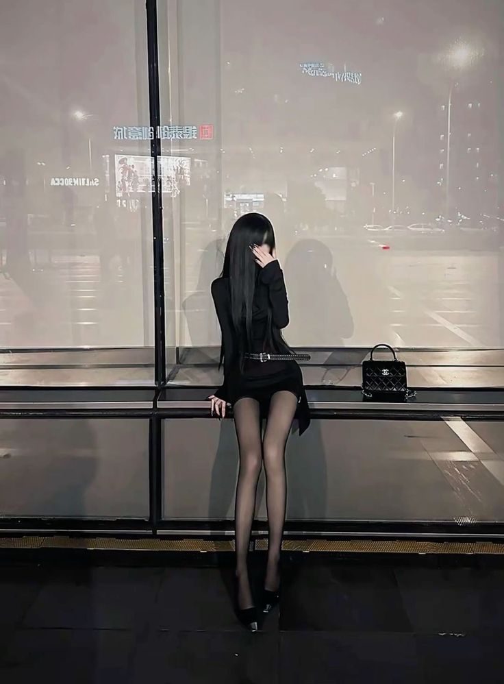 Woman with long black hair in a black dress and tights at night
