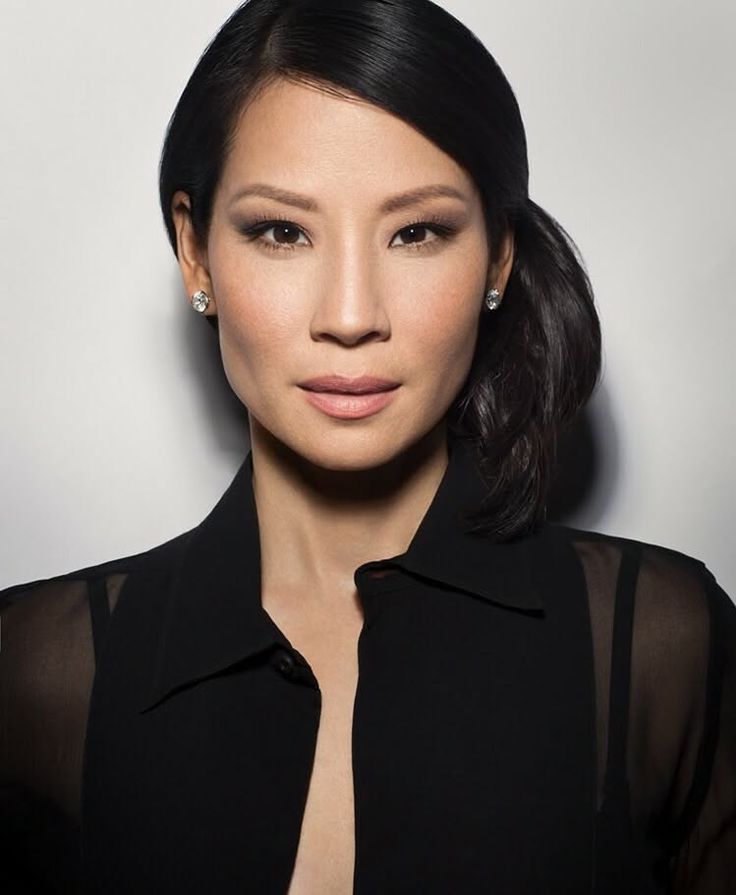 Woman with black hair and a black sheer-sleeved shirt looking at the camera