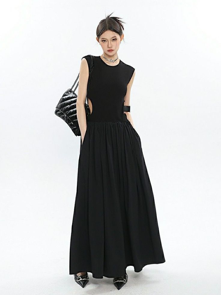 Woman in a black sleeveless dress with cut-outs and a black handbag